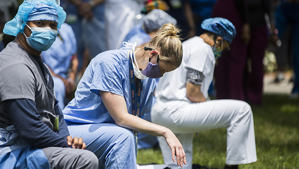 medical staff kneeling at a protest