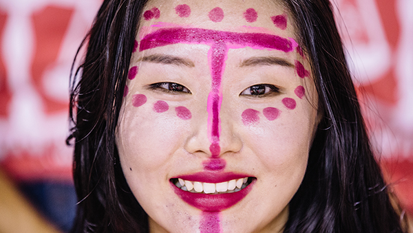 smiling student at songfest with magenta lipstick markings on her face