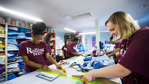 Rollins student volunteers in purple Rollinsteers t-shirts cutting fabric